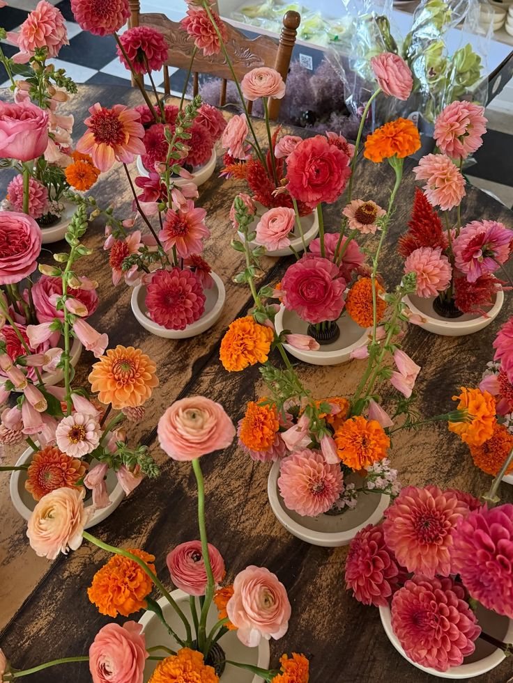 A long table of bud vases with dahlias and ranunculus