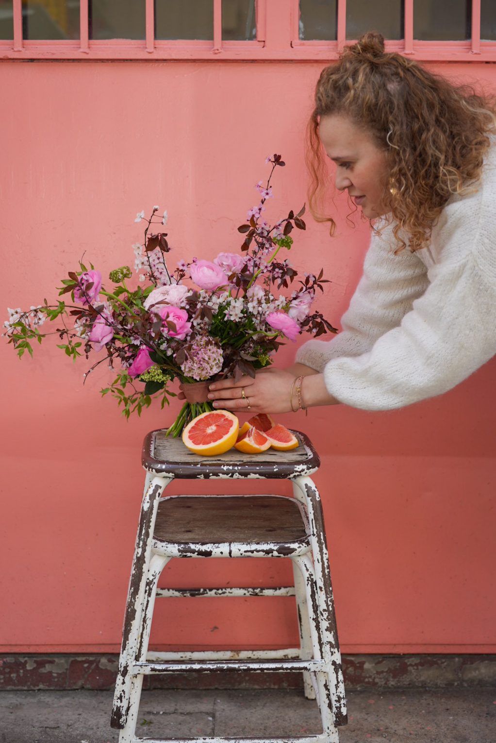 Agathe, founder of 5pm lab, composing a bouquet against a pink wall