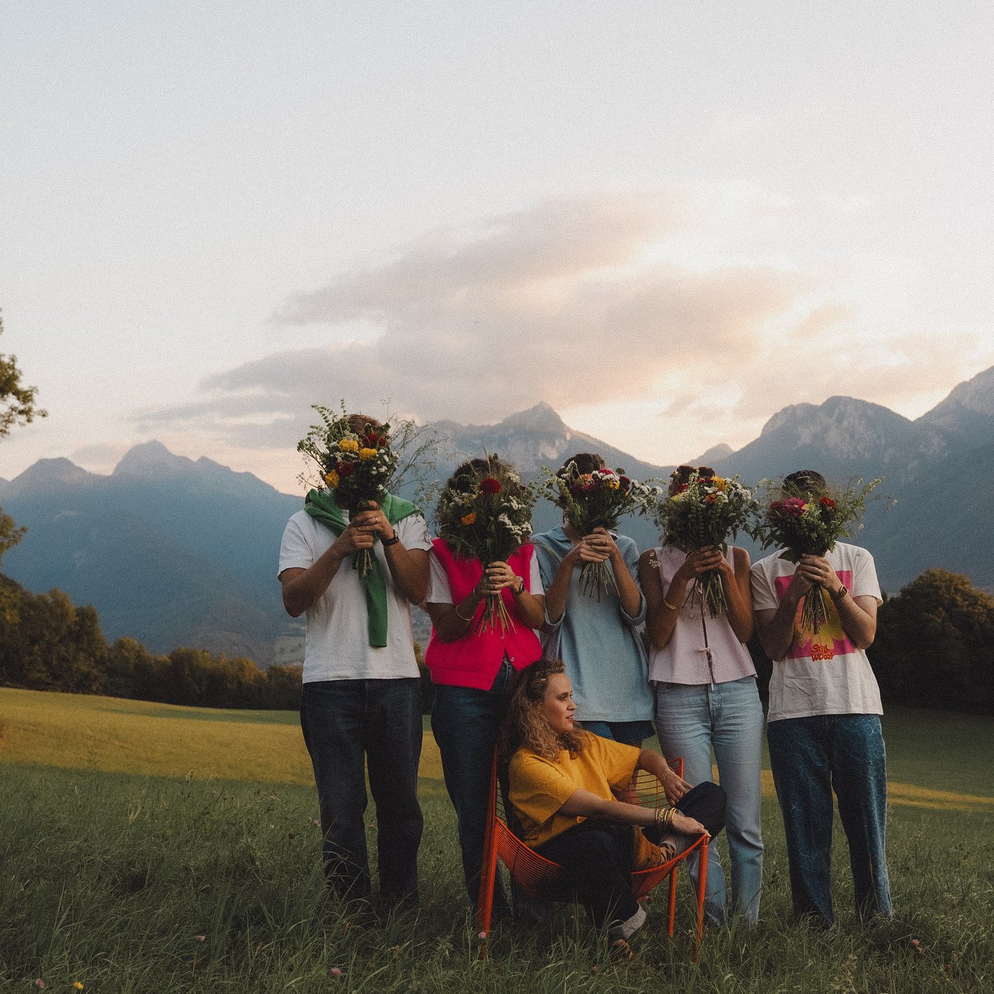 A team holding the bouquets they composed, mountains behind