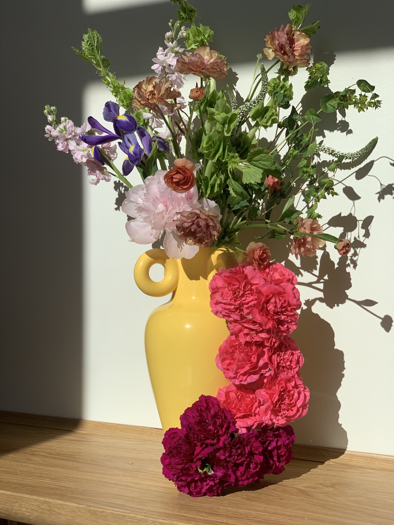 A cascade of carnations in a yellow amphora vase